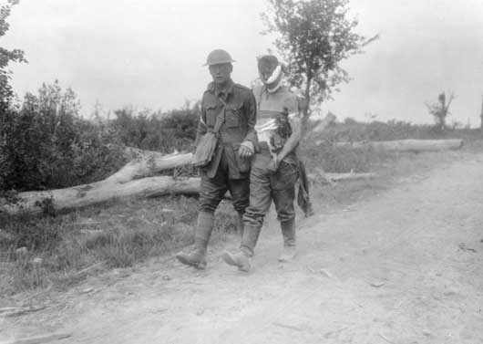 An Australian stretcher bearer assisting a wounded German prisoner during the Battle of Messines (AWM E00481).