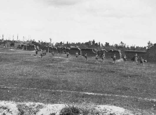 The 21st Battalion, having left the trench, start to go through the village at Mont St Quentin (AWM E03104).