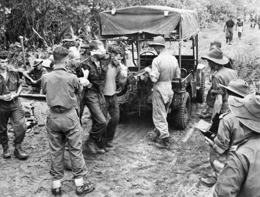 A wounded Australian soldier being helped to a jeep-ambulance on a forward track in Aitape Sector, New Guinea (AWM 018290).